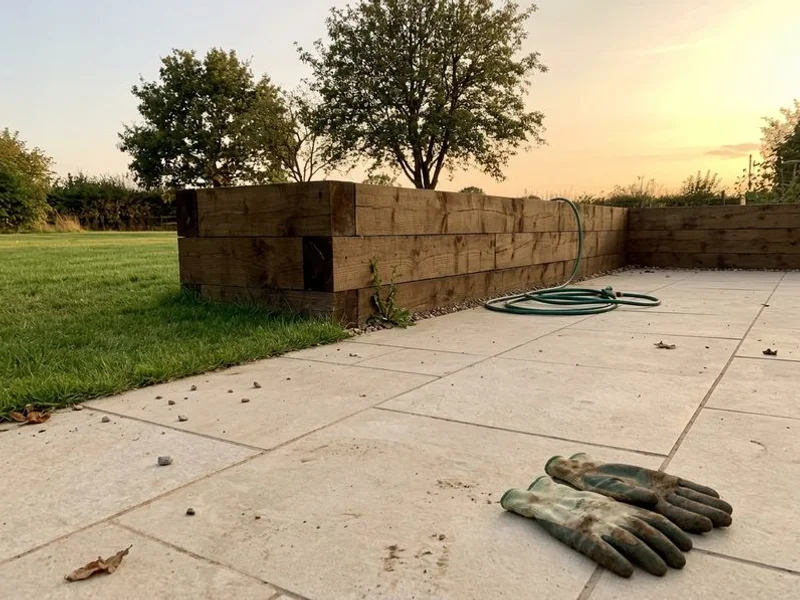 Porcelain paved patio with sleeper retaining wall in Cawston